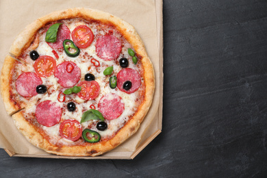 Photo of Delicious pizza Diablo in cardboard box on dark background, top view. Space for text