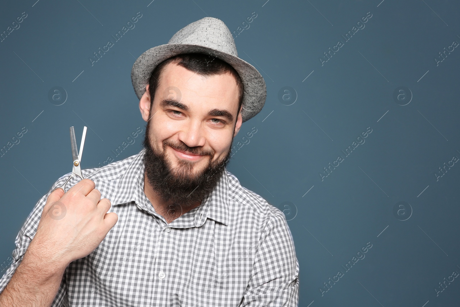 Photo of Professional hairdresser with scissors on color background