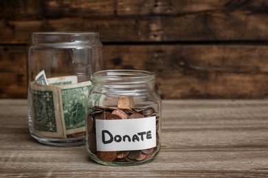 Photo of Donation jars with money on table. Space for text