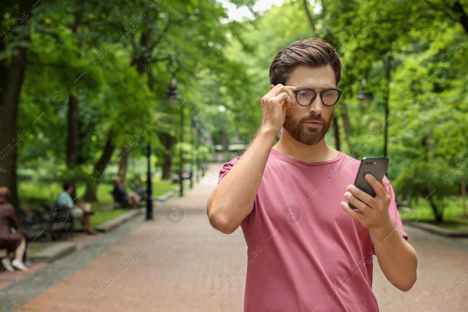 Photo of Handsome man using smartphone in park, space for text