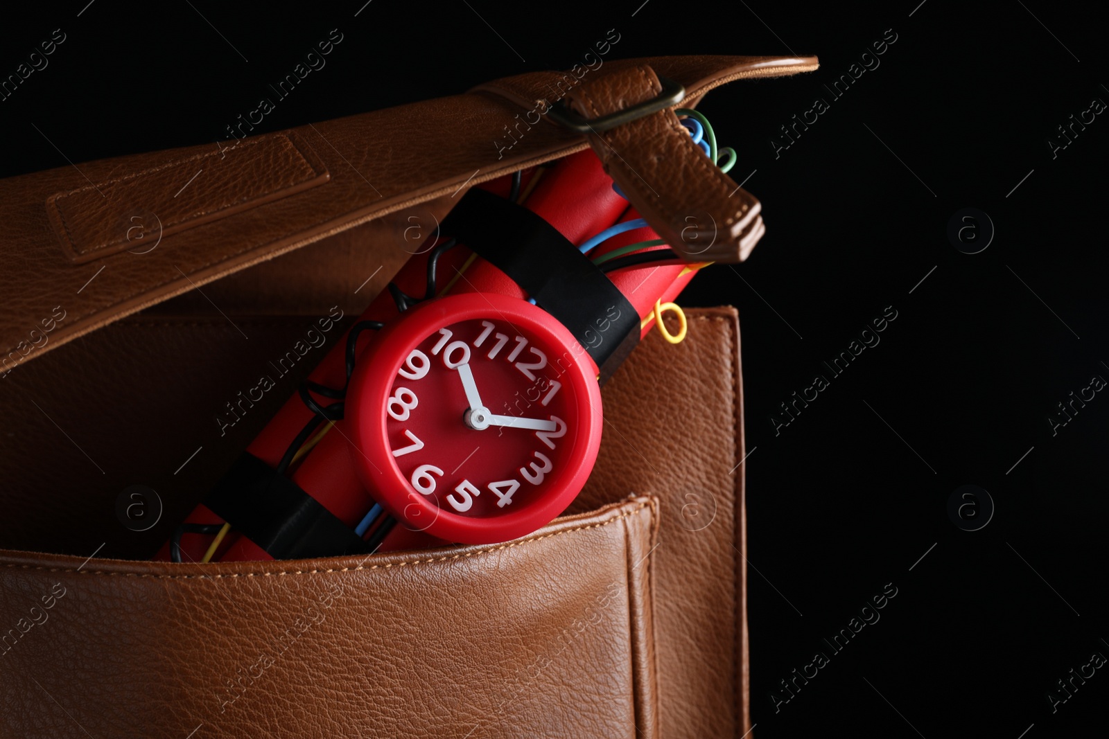 Photo of Leather briefcase with dynamite time bomb on black background, closeup. Space for text