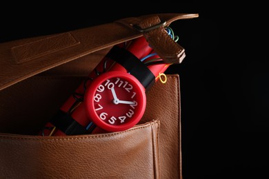 Photo of Leather briefcase with dynamite time bomb on black background, closeup. Space for text
