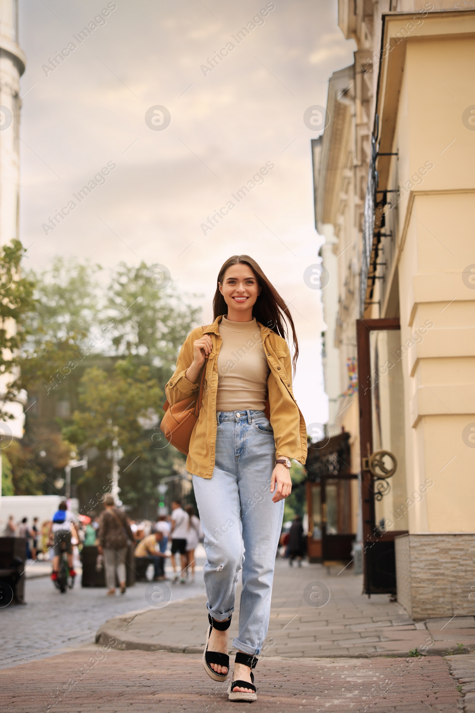 Photo of Young woman with backpack walking on city street