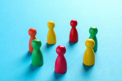 Photo of Colorful pawns on light blue background, closeup. Social inclusion concept