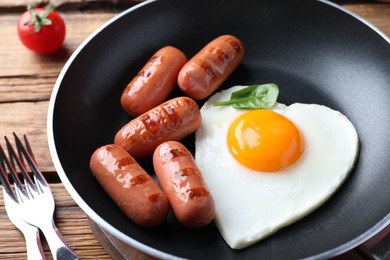 Photo of Romantic breakfast with fried sausages and heart shaped egg on wooden table, closeup. Valentine's day celebration