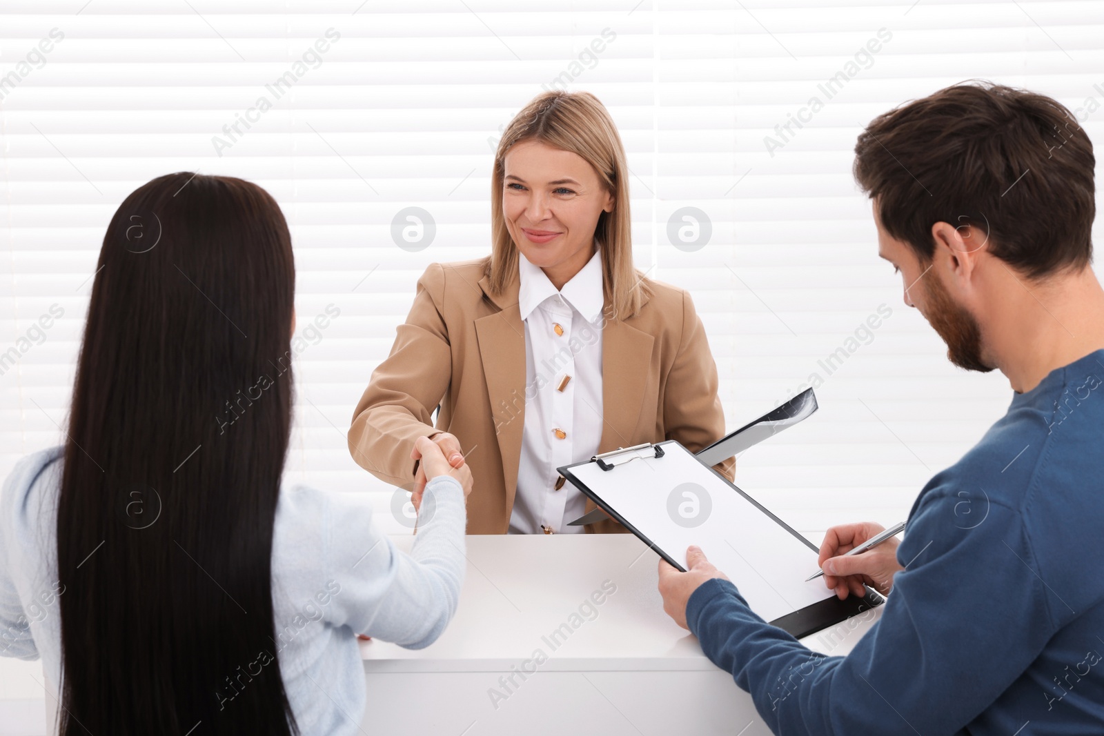 Photo of Real estate agent shaking hands with client at table in office