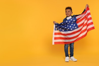 Photo of 4th of July - Independence Day of USA. Happy boy with American flag on yellow background, space for text