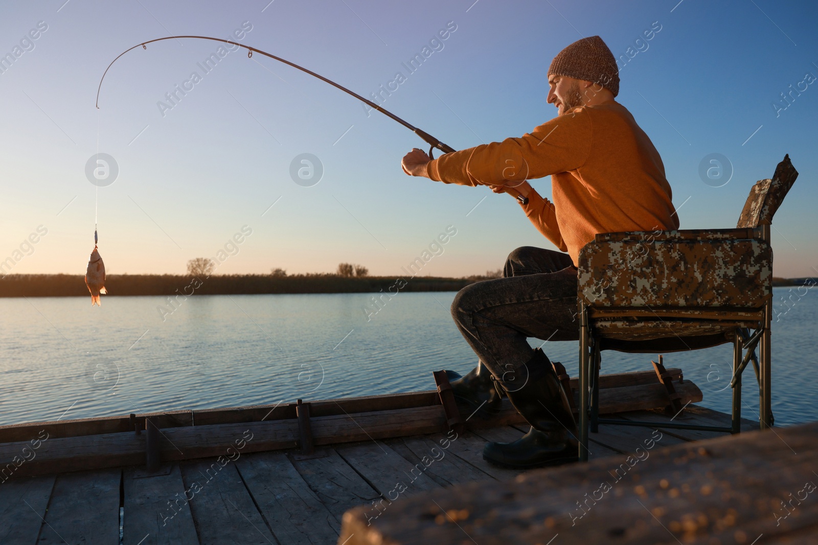 Photo of Fisherman catching fish with rod at riverside