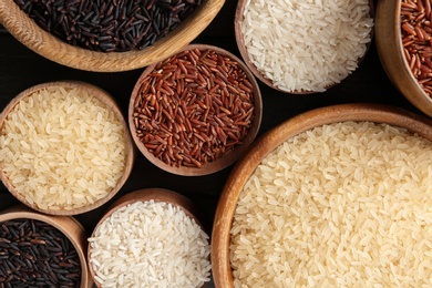 Photo of Flat lay composition with brown and other types of rice in bowls