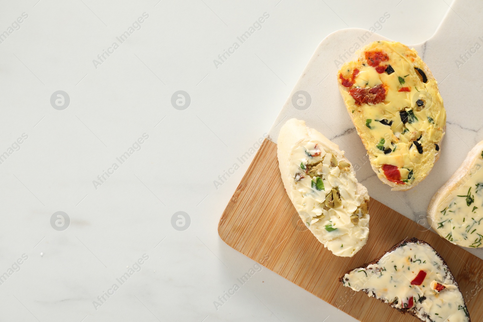 Photo of Different types of tasty butter and bread on white table, top view. Space for text