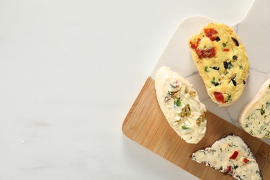 Photo of Different types of tasty butter and bread on white table, top view. Space for text