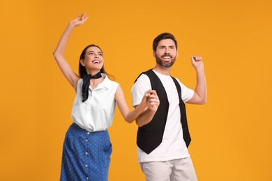 Photo of Happy couple dancing together on orange background