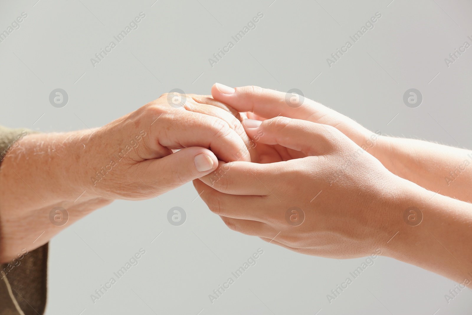 Photo of Helping hands on gray background, closeup. Elderly care concept