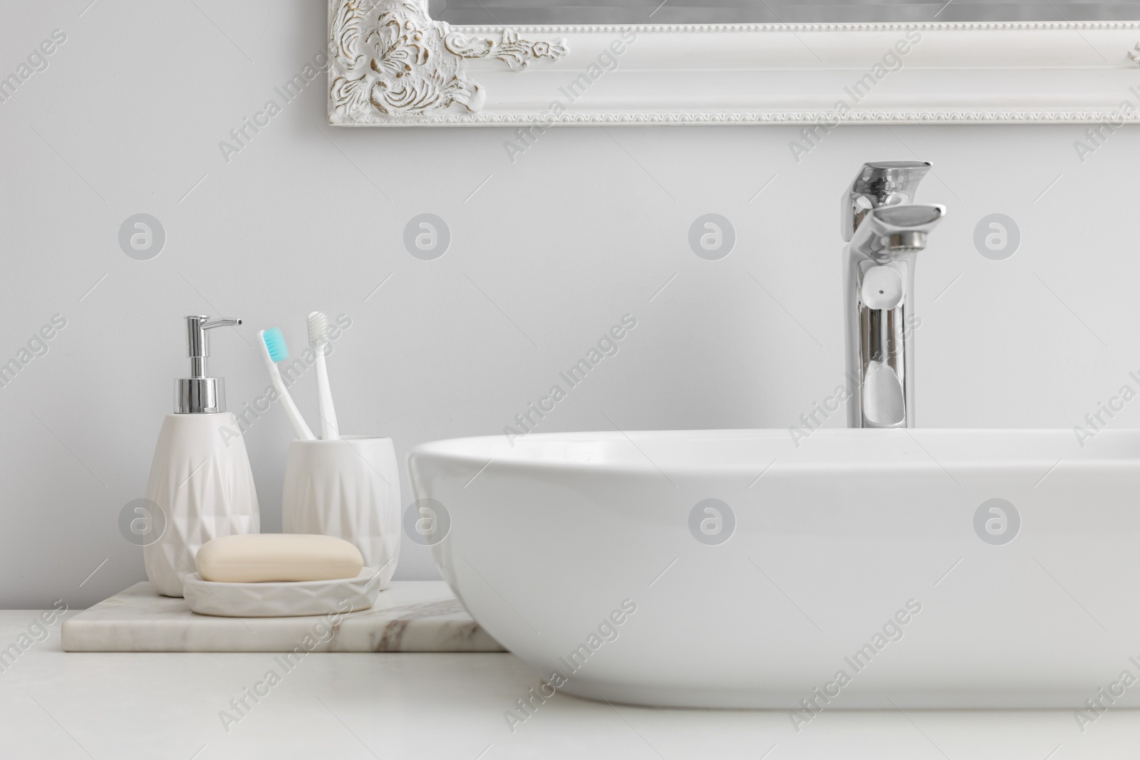 Photo of Different bath accessories and personal care products near sink on bathroom vanity