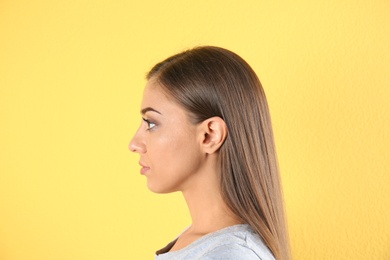 Young woman on color background. Hearing problem