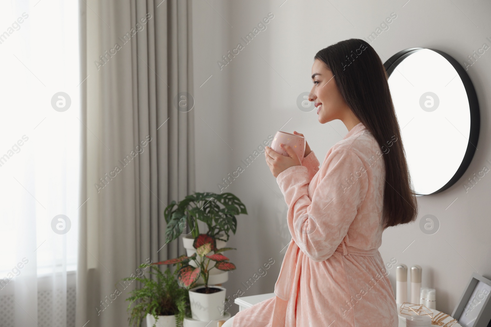 Photo of Young woman with cup of coffee at home. Morning routine