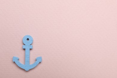 Photo of Anchor figure on pale pink background, top view. Space for text