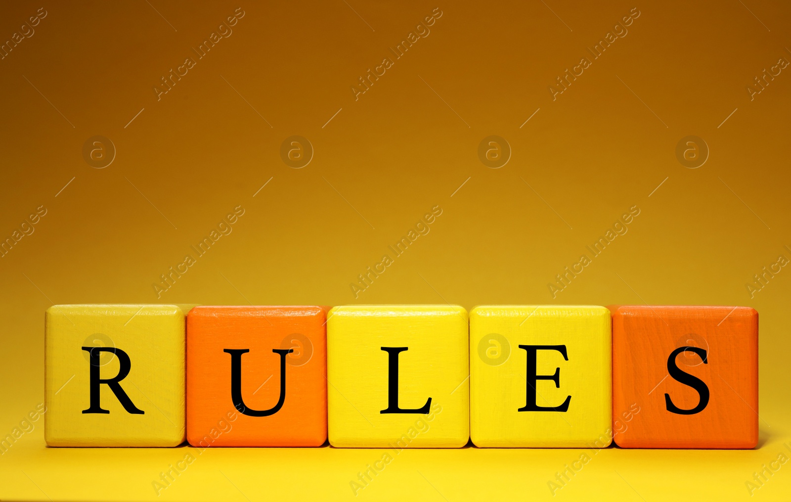 Photo of Word Rules made of colorful cubes with letters on dark yellow background, space for text