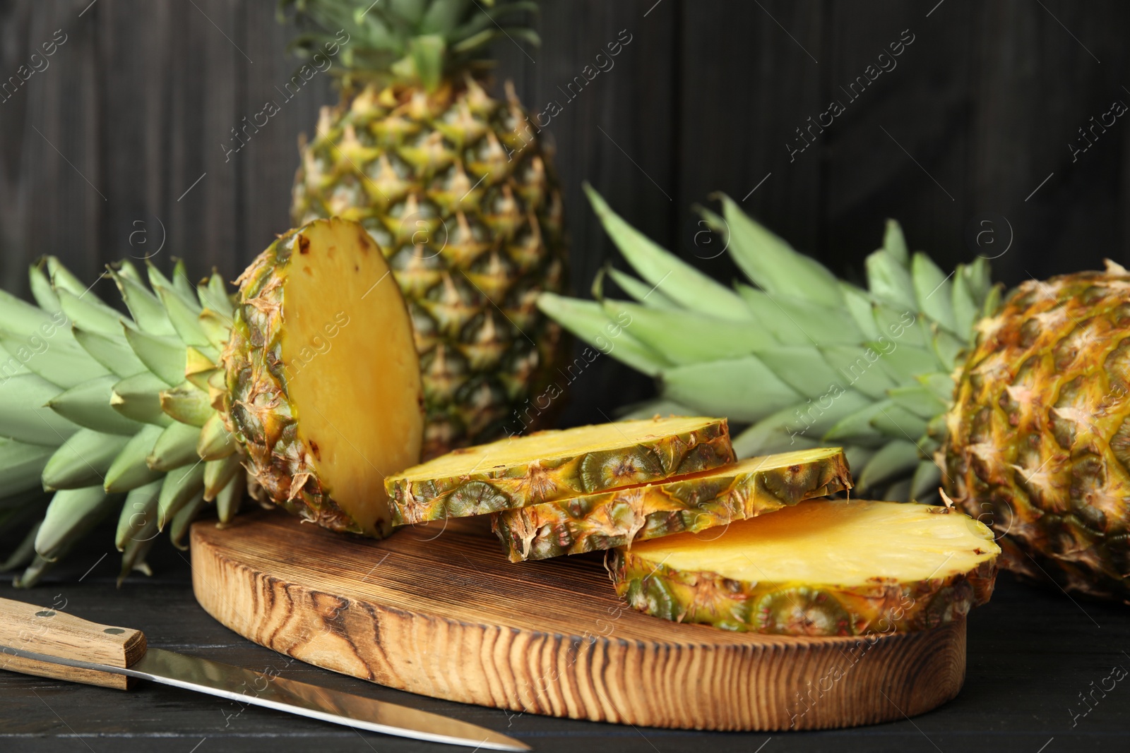 Photo of Cut fresh pineapples on black wooden table