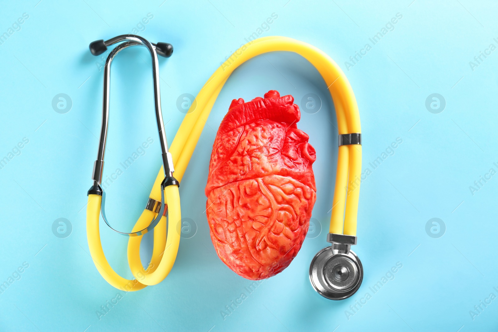 Photo of Stethoscope and model of heart on color background. Heart attack concept