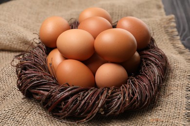 Photo of Fresh chicken eggs in nest on burlap fabric, closeup