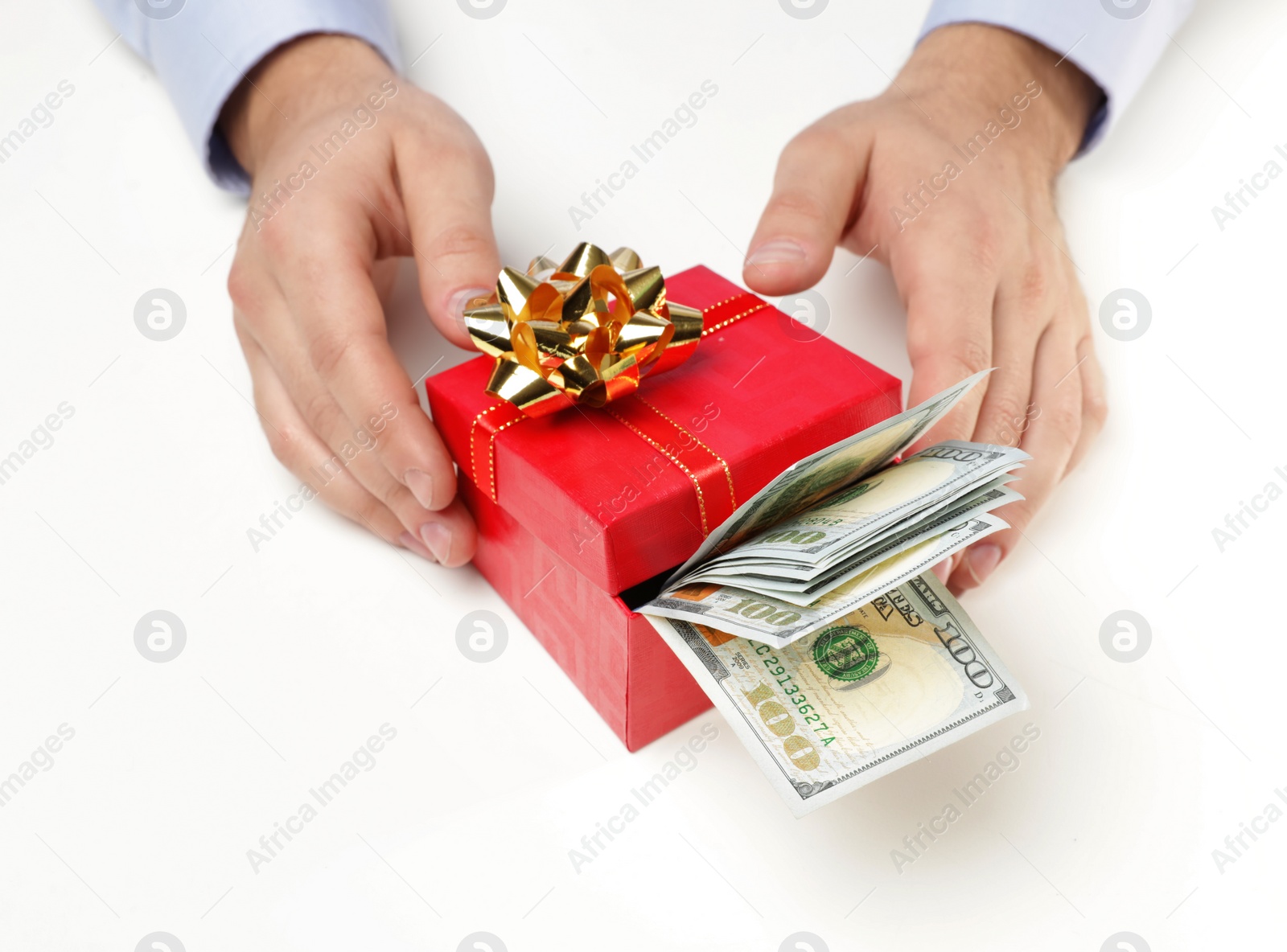 Photo of Man holding gift box with dollar banknotes on white background, closeup