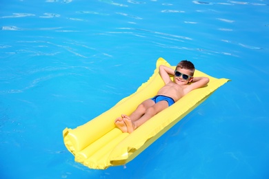 Little boy on inflatable mattress in swimming pool
