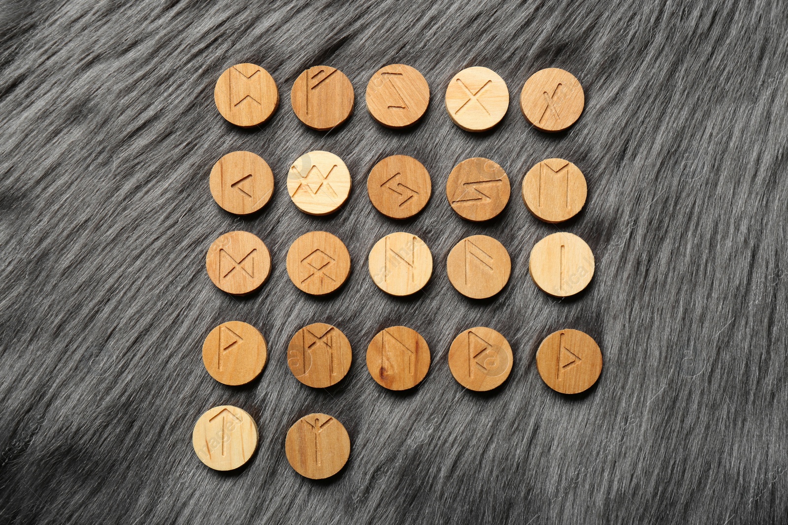 Photo of Many wooden runes on grey faux fur, flat lay