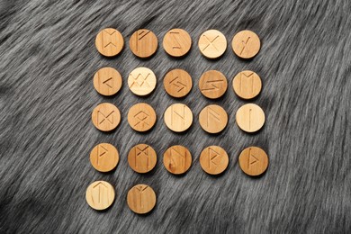Photo of Many wooden runes on grey faux fur, flat lay