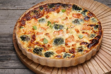 Photo of Pieces of delicious homemade quiche with salmon and broccoli on wooden board