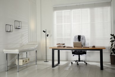 Modern medical office interior with doctor's workplace and examination table