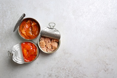 Tin cans with fish on grey table, flat lay. Space for text