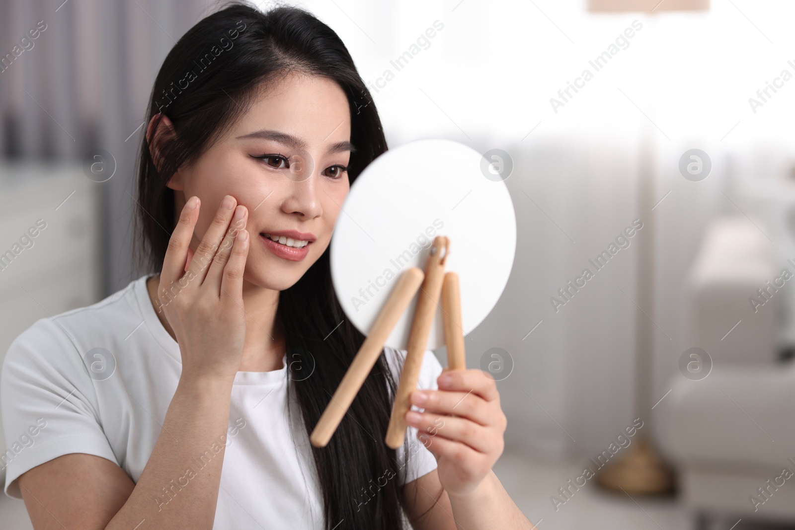 Photo of Woman with perfect skin looking at mirror indoors, space for text