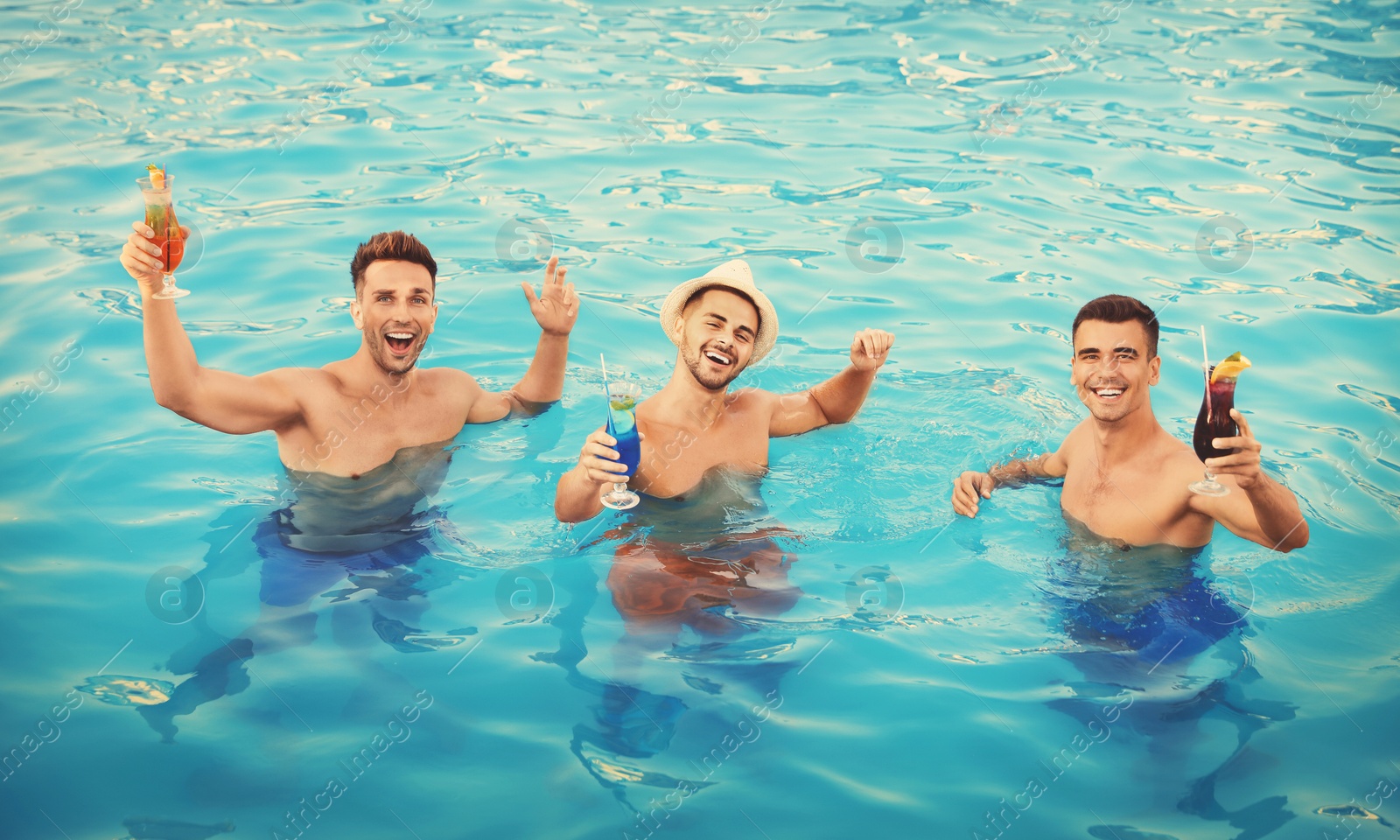 Image of Happy young friends with refreshing cocktails in swimming pool