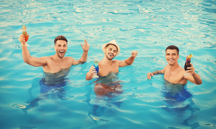 Image of Happy young friends with refreshing cocktails in swimming pool