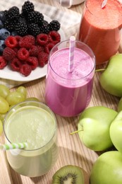 Glasses of different tasty smoothies and fresh ingredients on wooden table, above view