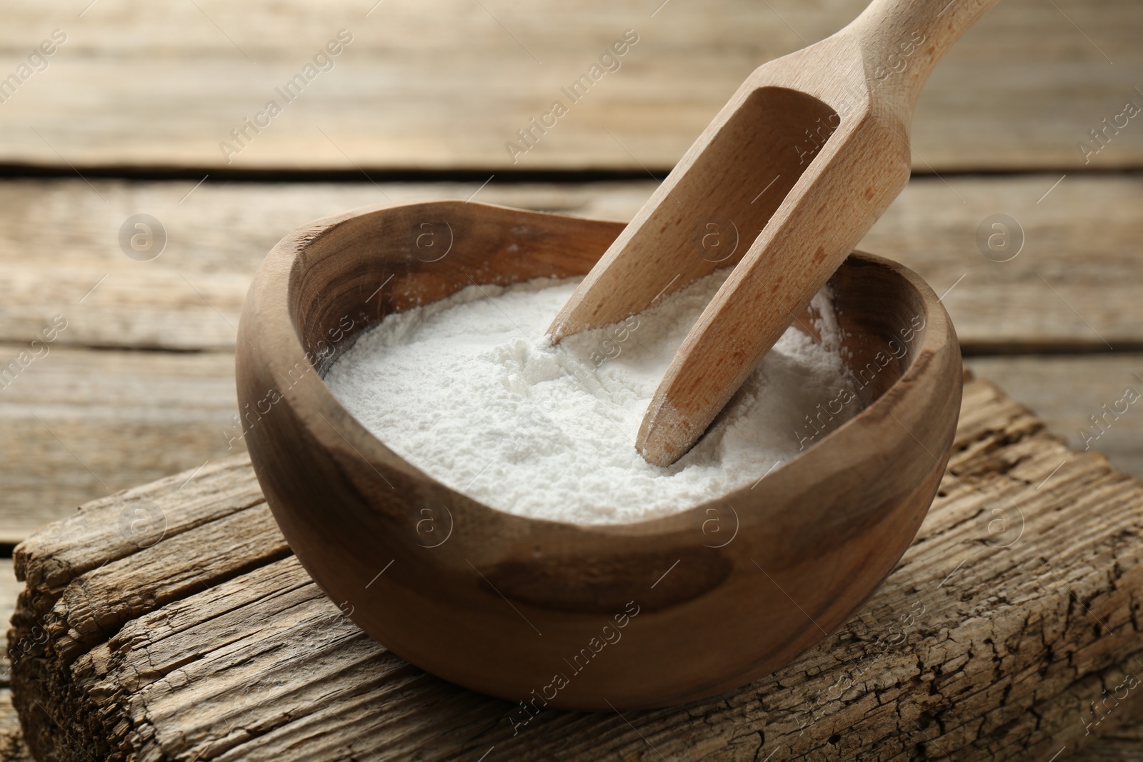 Photo of Baking powder in bowl and scoop on wooden table