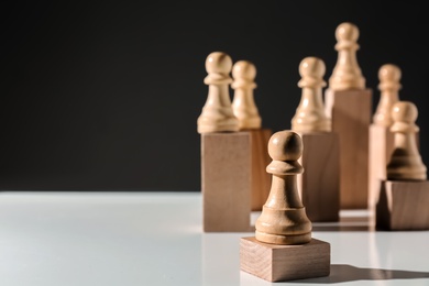 Photo of Pawns on white table against black background, space for text. Social roles concept