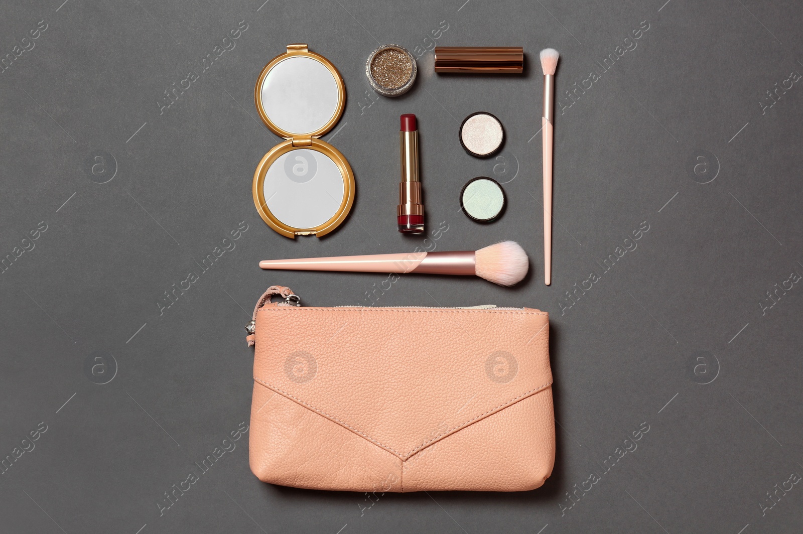 Photo of Cosmetic bag with makeup products on grey background, flat lay