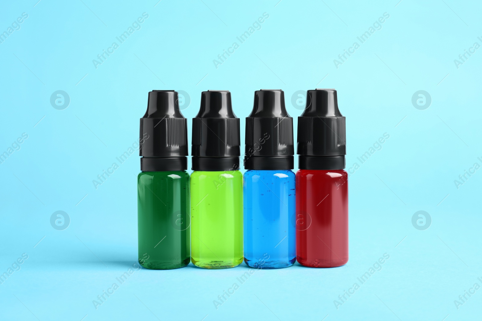 Photo of Bottles with different food coloring on light blue background