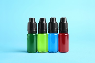 Photo of Bottles with different food coloring on light blue background