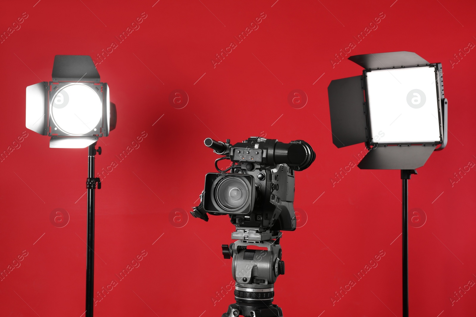 Photo of Professional video camera and lighting equipment on red background