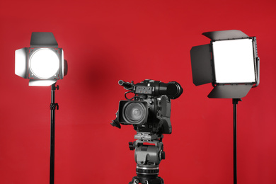 Photo of Professional video camera and lighting equipment on red background