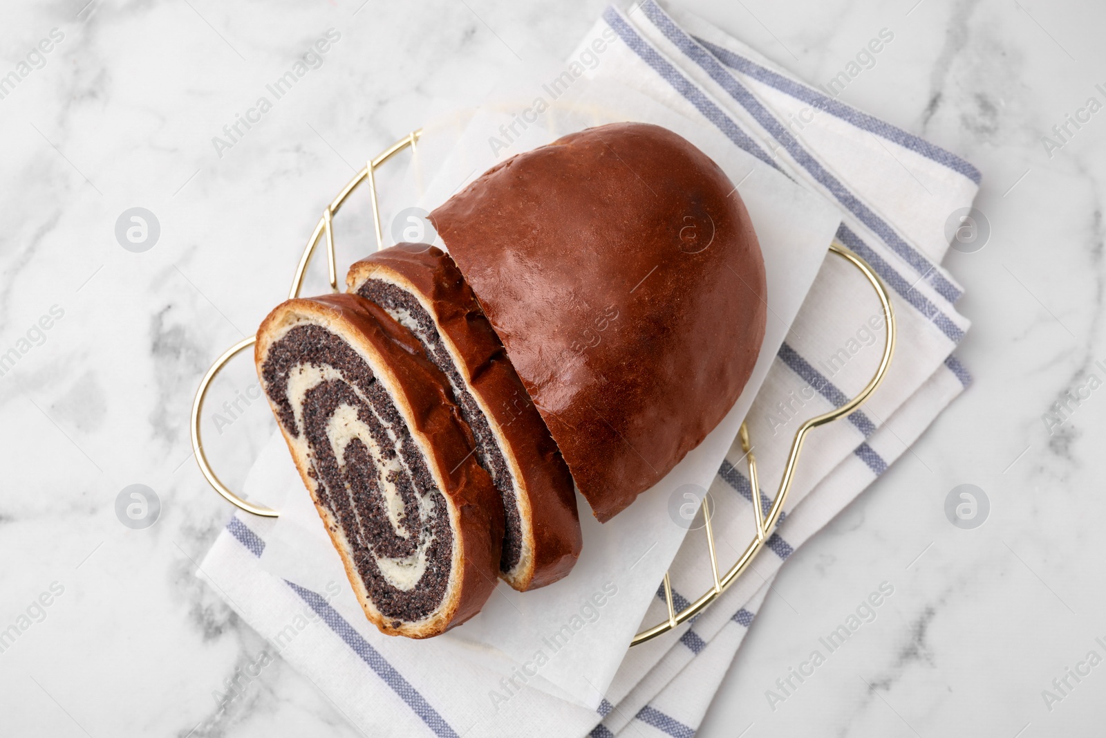 Photo of Slices of poppy seed roll on white marble table, top view. Tasty cake