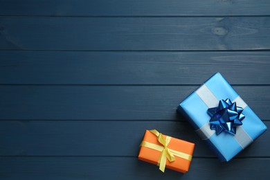 Photo of Colorful gift boxes on blue wooden table, flat lay. Space for text