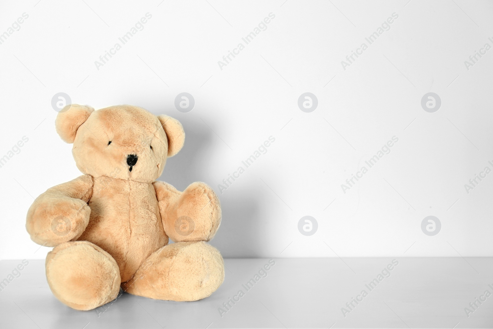 Photo of Teddy bear for baby room interior on table near white wall