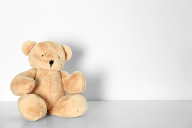 Photo of Teddy bear for baby room interior on table near white wall