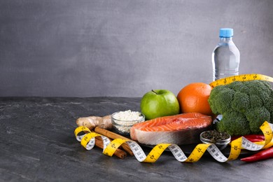Photo of Metabolism. Different food products and measuring tape on grey table, space for text