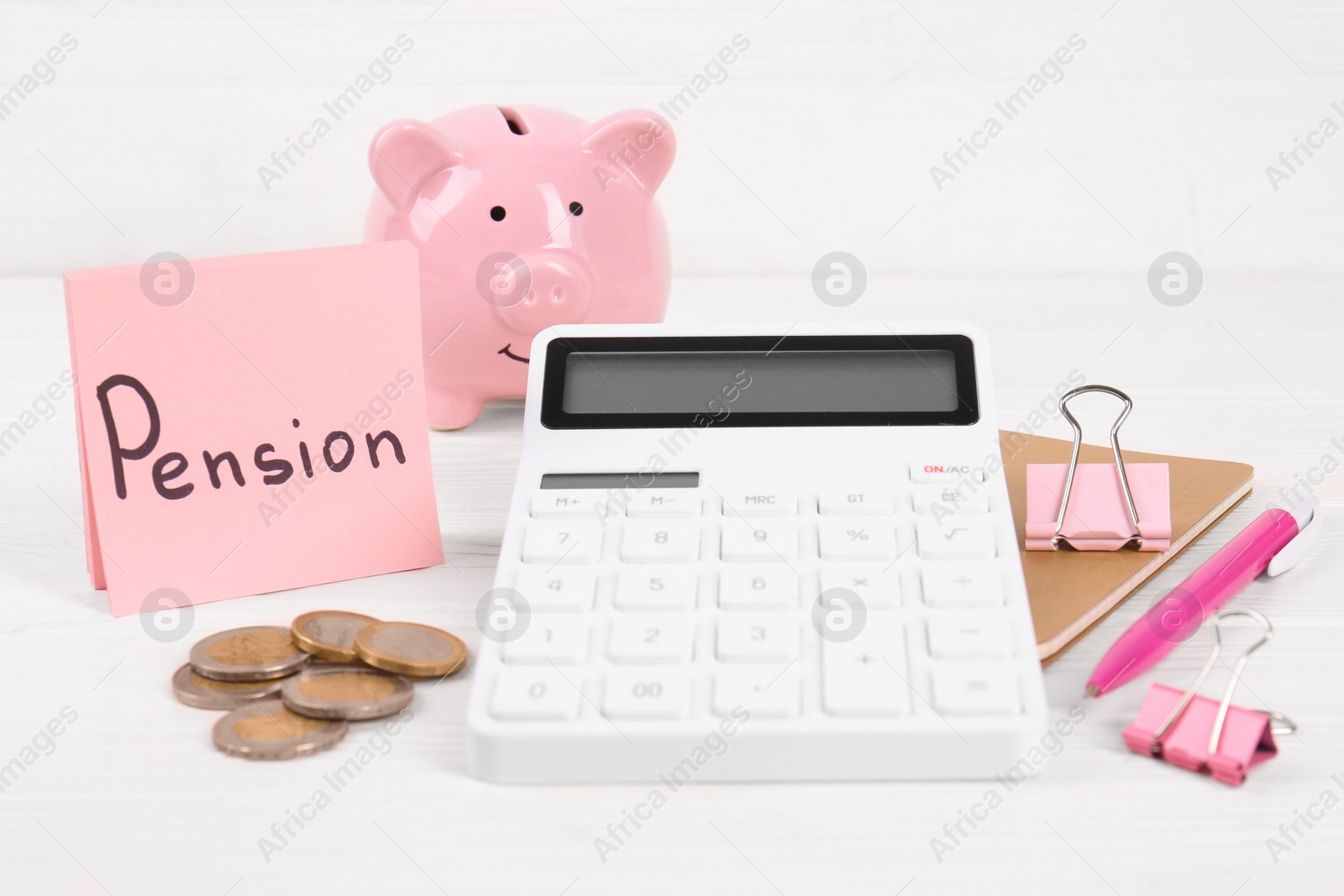 Photo of Calculator, coins, piggy bank, notebook, note with word Pension and pen on white table. Retirement concept