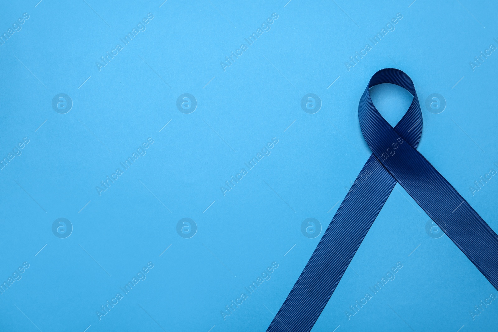 Photo of Blue awareness ribbon on color background, top view with space for text. Symbol of social and medical issues